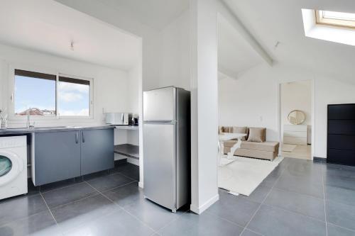 une cuisine avec un réfrigérateur et un salon dans l'établissement Le Nova - 2 Prs - Wifi - Proche Paris, à Aubervilliers