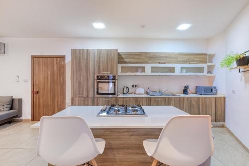 a kitchen with two white chairs and a counter at Bright,stylish 2bedroom apartment in village centre in Kalkara