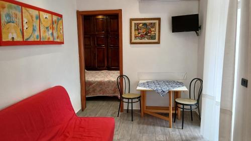 a room with a red couch and a table and chairs at Appartamento Torrione in Piani di Vallecrosia