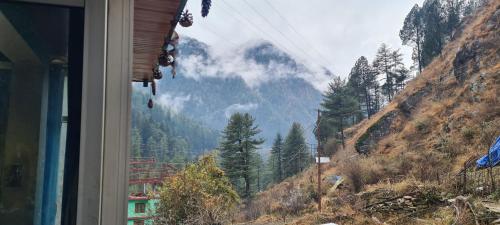 a view of a mountain from a window of a house at Formosa cafe & hostel in Kasol