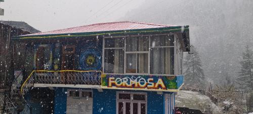 a building in the snow with a sign on it at Formosa cafe & hostel in Kasol