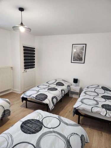 3 lits dans une chambre dotée de murs blancs et de parquet dans l'établissement Appartement meublé 6 personnes à deux pas du centre-ville, à Saint-Dizier