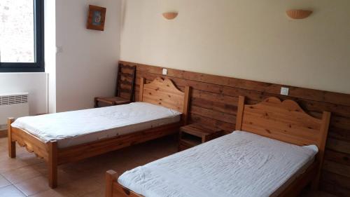 deux lits jumeaux dans une chambre aux murs en bois dans l'établissement Gîte La Remise 6 pers. du samedi au samedi, à Saint-Privat
