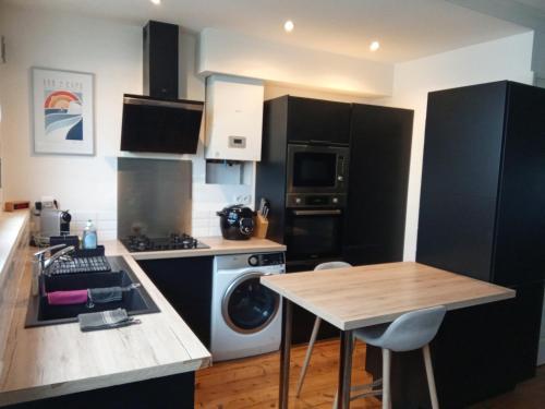 une cuisine avec des armoires noires et un lave-linge/sèche-linge dans l'établissement Lille Parvis St Michel, à Lille