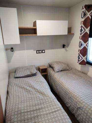 deux lits côte à côte dans une chambre dans l'établissement Jolie Mobil Home climatisé 58, à Saint-Jean-de-Monts