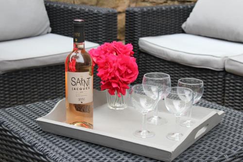 - une bouteille de vin et des verres sur un plateau avec une fleur dans l'établissement Gîte La Remise 6 pers. du samedi au samedi, à Saint-Privat