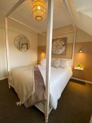a bedroom with a four poster bed with a chandelier at Bowness Bay View in Windermere