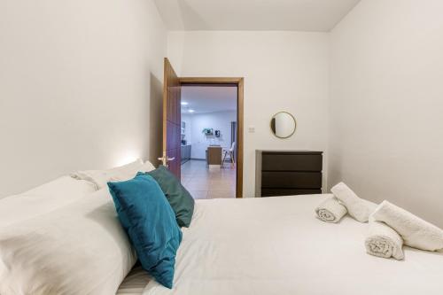 a bedroom with a white bed with blue pillows at Bright,stylish 2bedroom apartment in village centre in Kalkara
