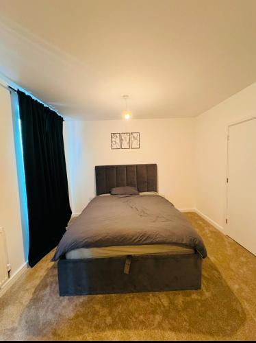 a bedroom with a large bed with black curtains at Beautiful King Sized En-suite Room - Anderson Home in Dagenham Dock