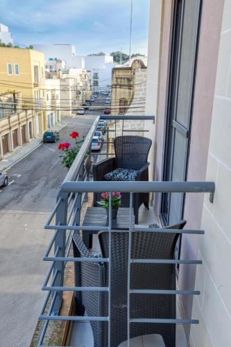 a balcony with chairs and flowers on a building at Bright,stylish 2bedroom apartment in village centre in Kalkara