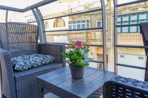 a table with a potted plant on a balcony at Bright,stylish 2bedroom apartment in village centre in Kalkara