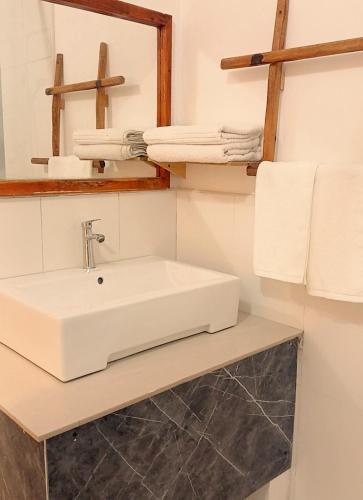 a bathroom with a sink and a mirror and towels at Island Grand Maldives in Hangnaameedhoo
