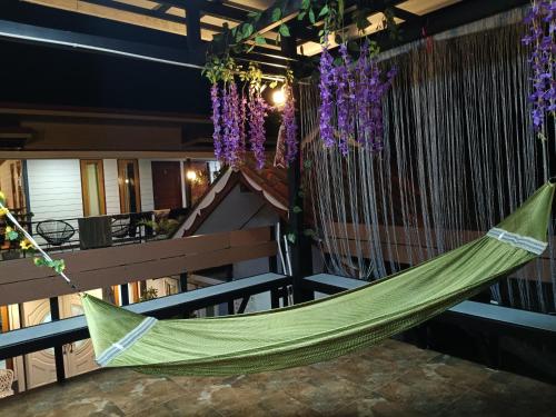 a green hammock on a balcony with purple flowers at Cherlyn Homestay เฌอลินน์โฮมสเตย์ เกาะลิบง in Ban Batubute
