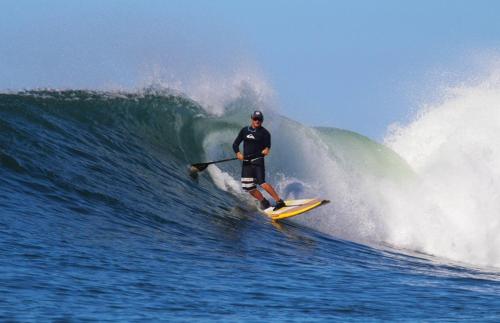 a man riding a wave on a surfboard in the ocean at OceanFront Bungalows - Paradise Rentals in Santa Catalina