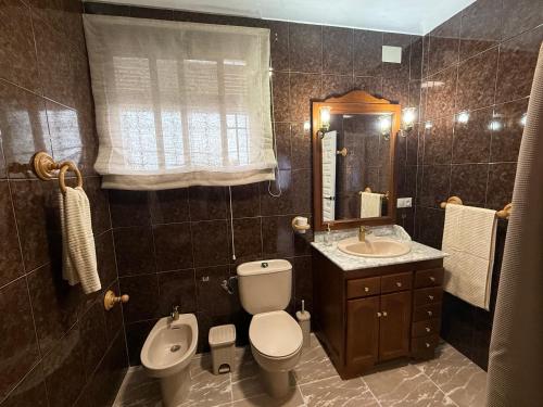 Un baño con inodoro, lavabo y espejo. en Meloja Centro, en Hornachuelos