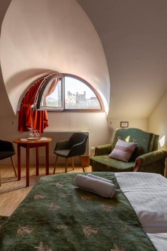 a room with a bed and a couch and a window at Vár Vendéglő Panzió in Sárospatak