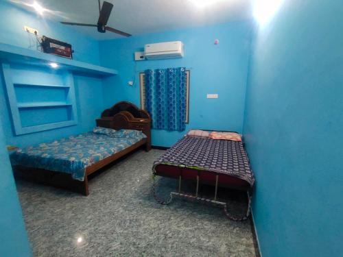 a room with two beds in a blue room at Durai Ac rooms in Peralam Junction