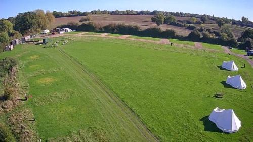 an aerial view of a large green field with tents at Mousley House Farm Campsite and Glamping in Warwick