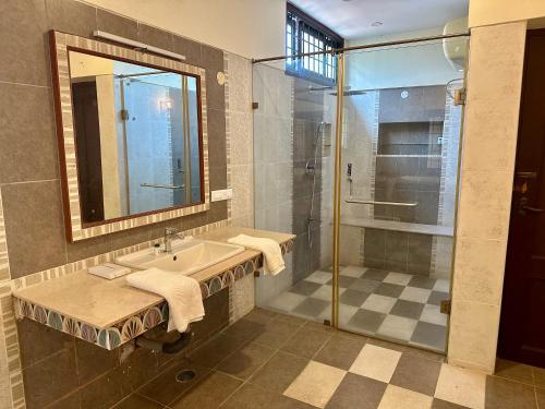 a bathroom with a shower and a sink and a mirror at Costa Verde Luxury Seafront Villa in Chennai