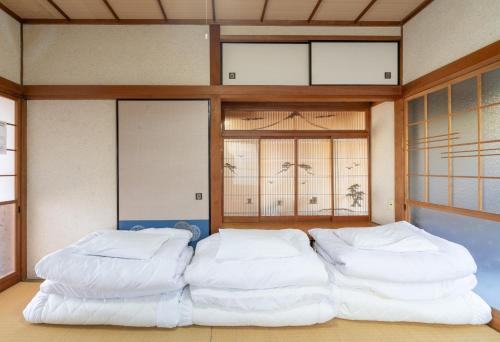 a room with two large white beds in it at 古民家民泊ーよかよー in Kawatana