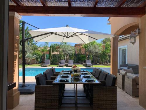 - une table à manger avec un parasol en face de la piscine dans l'établissement Villa Giovanna à Saint-Raphaël avec piscine chauffée, à Saint-Raphaël
