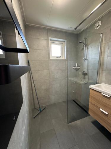 a bathroom with a glass shower and a sink at Vakantiehuis nr 165 Lauwersmeer met sauna in Anjum