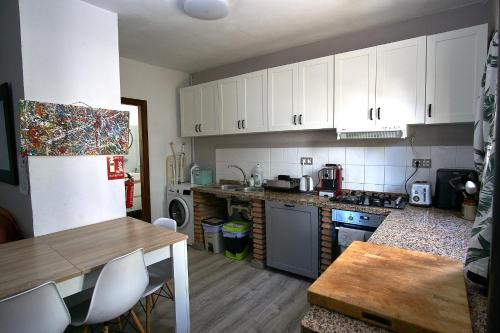 a kitchen with white cabinets and a table and a counter top at Olive Branch El Chorro in El Chorro