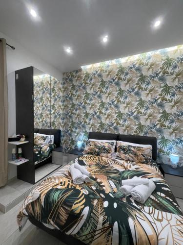 a bedroom with a large bed with a tropical wallpaper at Nigalù House in Naples