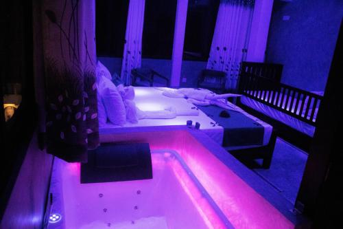 a room with a bed and a tub with purple lights at A2 HavenX in Hikkaduwa