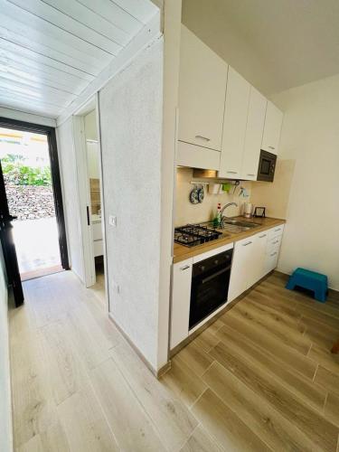 a kitchen with white cabinets and a wooden floor at Residence Oasi La Cinta Centro in San Teodoro
