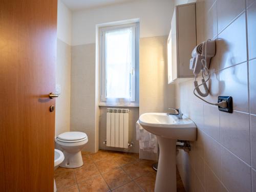 a bathroom with a sink and a toilet and a window at My Holidays New Eden Mansarda in Domaso