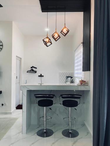 a kitchen with a counter with two bar stools at D'Lamp Studio in Kampung Kuala Besut