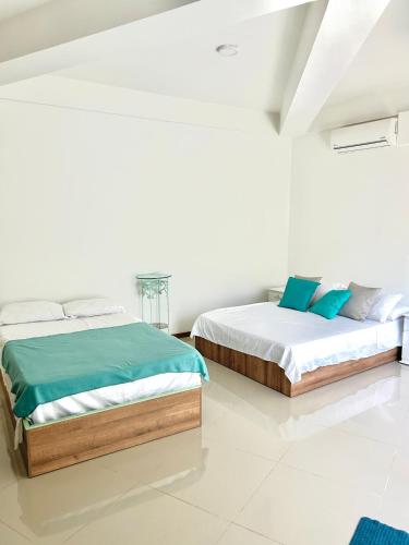 two beds in a bedroom with white walls at Apartamento Vacacional San Jerónimo in Medellín