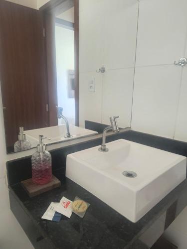 a bathroom with a white sink and a mirror at Lindo apto em frente ao Mar - Ilhéus - Itacaré Ba in Ilhéus