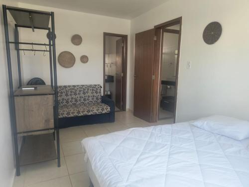 a bedroom with a white bed and a couch at Lindo apto em frente ao Mar - Ilhéus - Itacaré Ba in Ilhéus