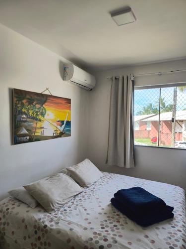 a bedroom with a bed with a blue pillow on it at Lindo apto em frente ao Mar - Ilhéus - Itacaré Ba in Ilhéus