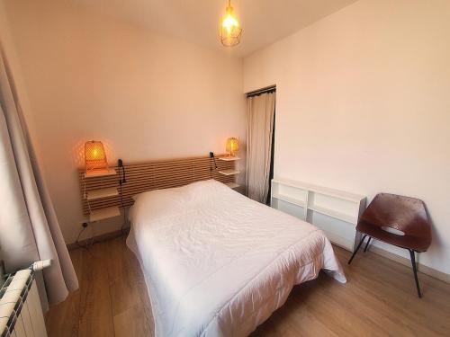 une chambre avec un lit blanc et une chaise dans l'établissement Grand appartement, 4 chambres au cœur du Mourillon, à Toulon