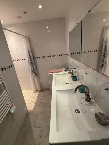 une salle de bain blanche avec deux lavabos et un miroir dans l'établissement le Gite de la Bergerie, à Amboise