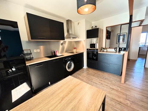 une cuisine avec des armoires noires et un lave-linge/sèche-linge dans l'établissement Les Terrasses du Zenith - Parking - Tramway - Wifi, à Toulouse