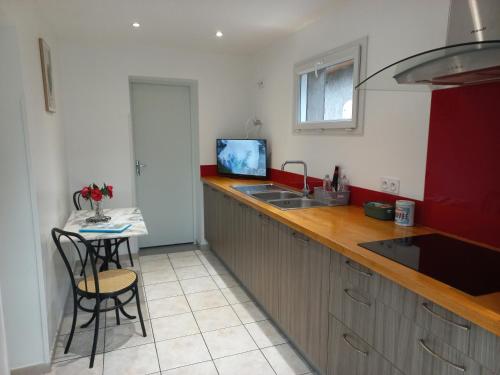 a kitchen with a sink and a counter with a table at Appartement avec jardin in Adé
