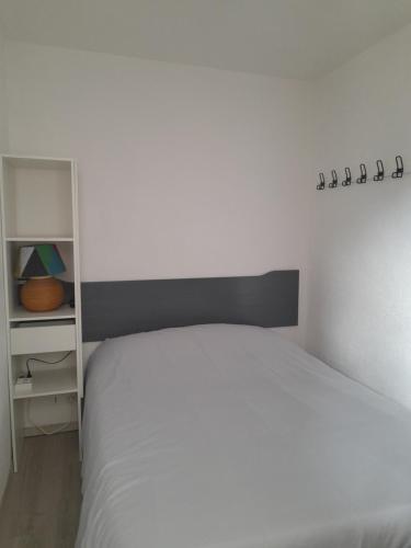 a bedroom with a white bed and a shelf at Appartement au cœur de la Marina in Sète
