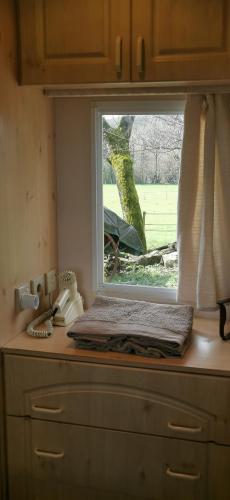 - une fenêtre au-dessus d'une commode dans une cuisine dans l'établissement Gîte dans ancien corps de ferme à 5mn de Pompadour, à Troche