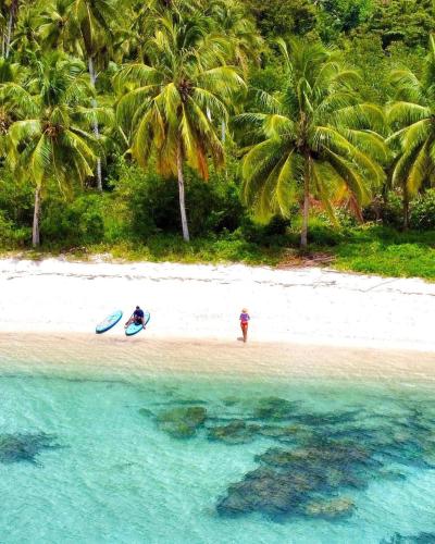 two people standing on a beach with palm trees at Cabang Campsite - Private Island Experience in San Vicente
