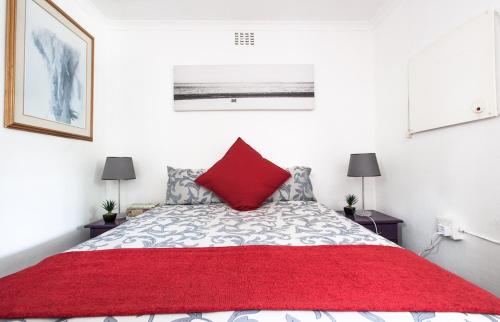 a bedroom with a red pillow on a bed at Garden Cottage in Richmond nr Melville in Johannesburg