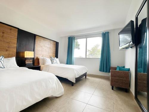 a hotel room with two beds and a flat screen tv at Beach Apartment At Nikki Residences 2 Bedroom in El Chirú
