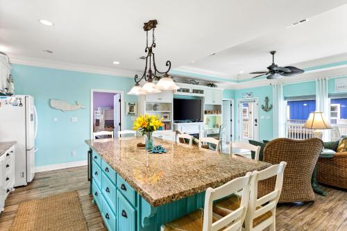a kitchen with blue cabinets and a large island with flowers on it at Sconset South 4BR Beach Escape! Deck, Bar, Games & Gulf Views in Port Bolivar