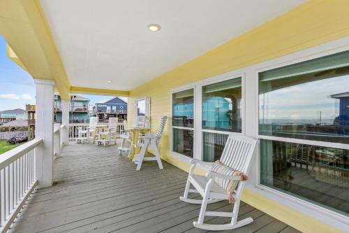 a porch with white chairs and tables and windows at Sconset South 4BR Beach Escape! Deck, Bar, Games & Gulf Views in Port Bolivar