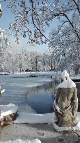 a statue of a woman sitting next to a pond in the snow at Mobilhome convivial en Alsace in Munster