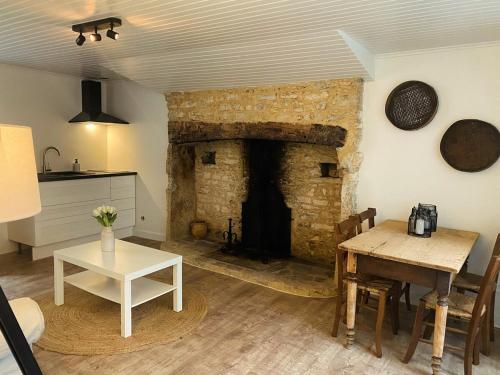 a living room with a table and a stone fireplace at La Petite Maison du Moulin in Salviac