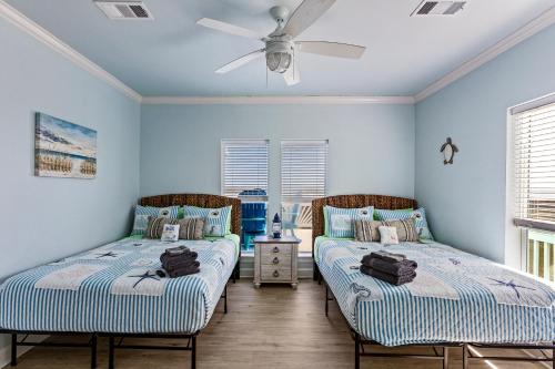 two beds in a room with blue walls and windows at Beachfront Hideaway! Luxury Beachfront, SwimSpa, Game Room, Firepit by Bolivar Vacations in Port Bolivar